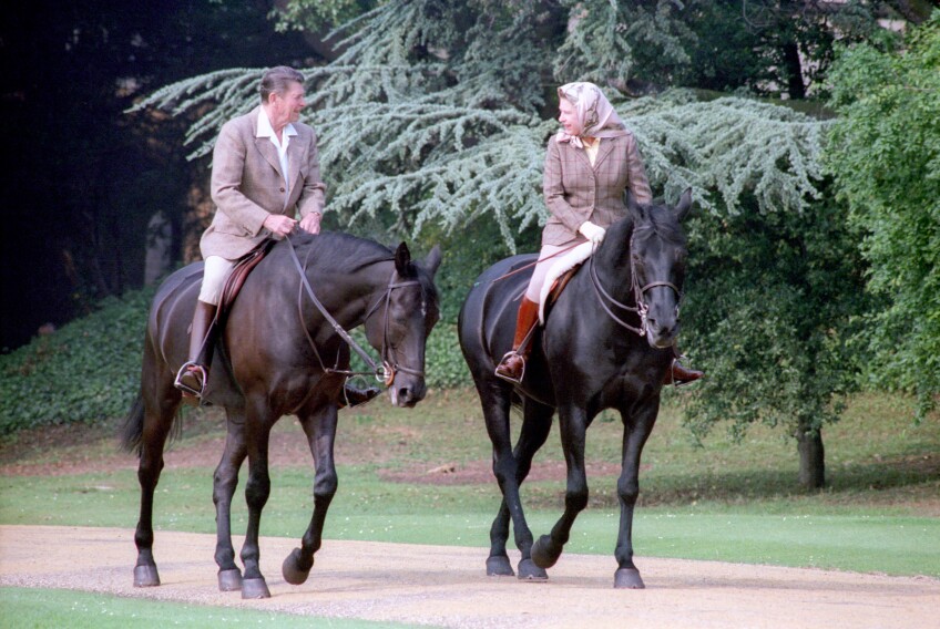 President Ronald Reagan (left) and Queen Elizabeth II (right) on horseback on a dirt path at Windsor Castle