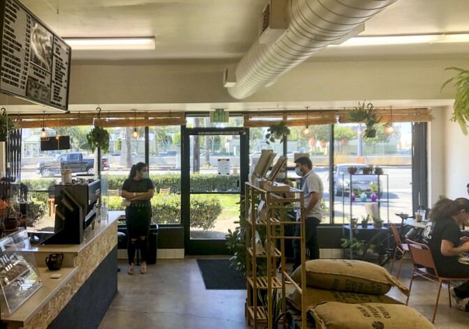 The interior of Patria Coffee. Customers wait by the counter for their orders.