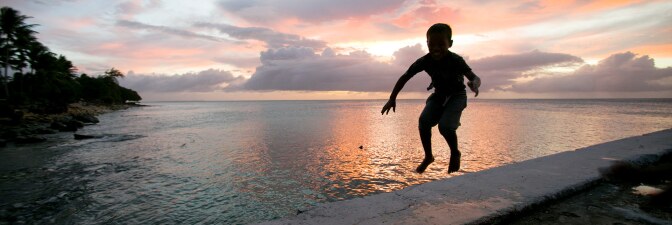 A little boy jumps near the ocean surrounding the Marshall Islands, which are at high risk due to sea level rise. | Courtesy of Thomson Reuters Foundation