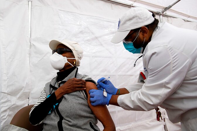 Dr. Jerry P. Abraham administers a COVID-19 vaccination to a senior citizen in a vaccination tent at the Kedren Community Health Center on January 25, 2021 in Los Angeles, California.