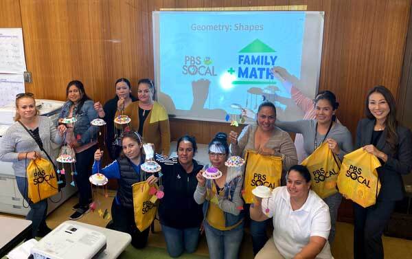 A group of caregivers hold their completed shape mobiles.