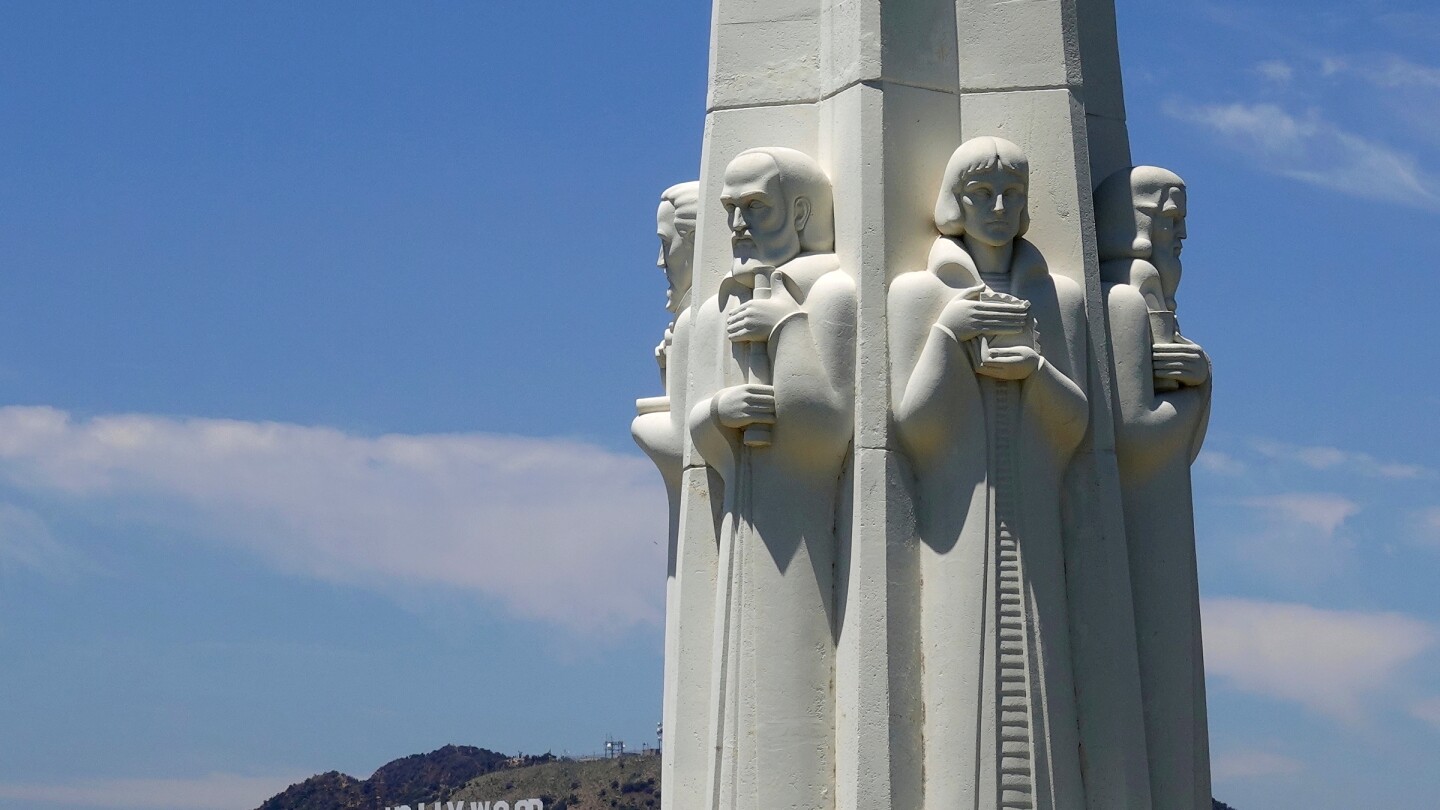 A monument that depicts some astronomers in the foreground with the Hollywood sign in the background.