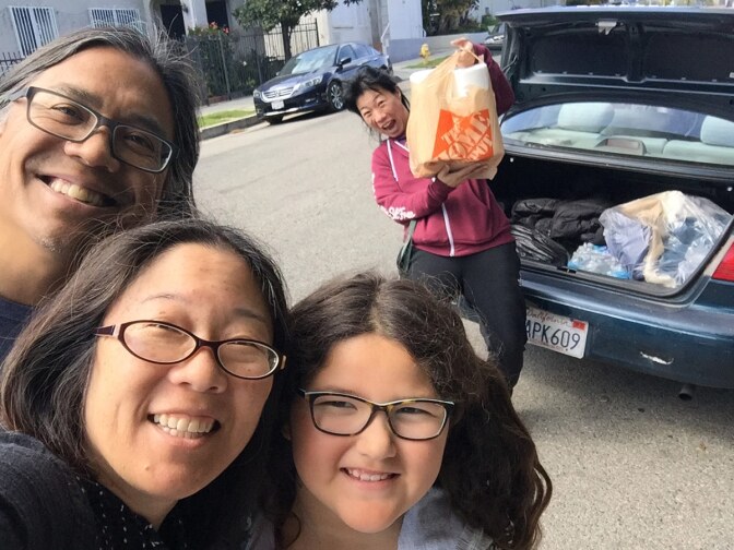 In the very beginning, Gayle Isa and family pick up their first batch of fabric to cut from friend turned Auntie "Overlord” Kristina Wong. | Photo by Gayle Isa/Courtesy of Auntie Sewing Squad