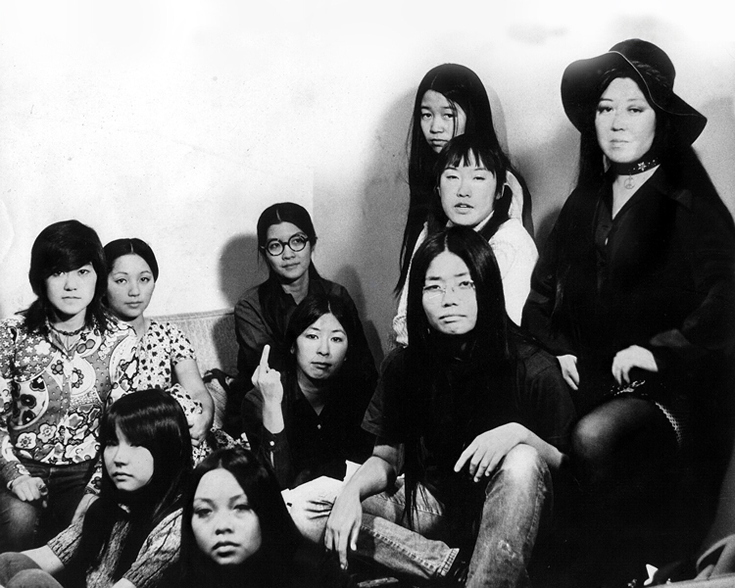 A black and white photo of the women of the Gidra staff taken portrait style. They are all gathered around a couch and look into the camera with a serious and striking expression on their faces. One of the women is holding up her middle finger.
