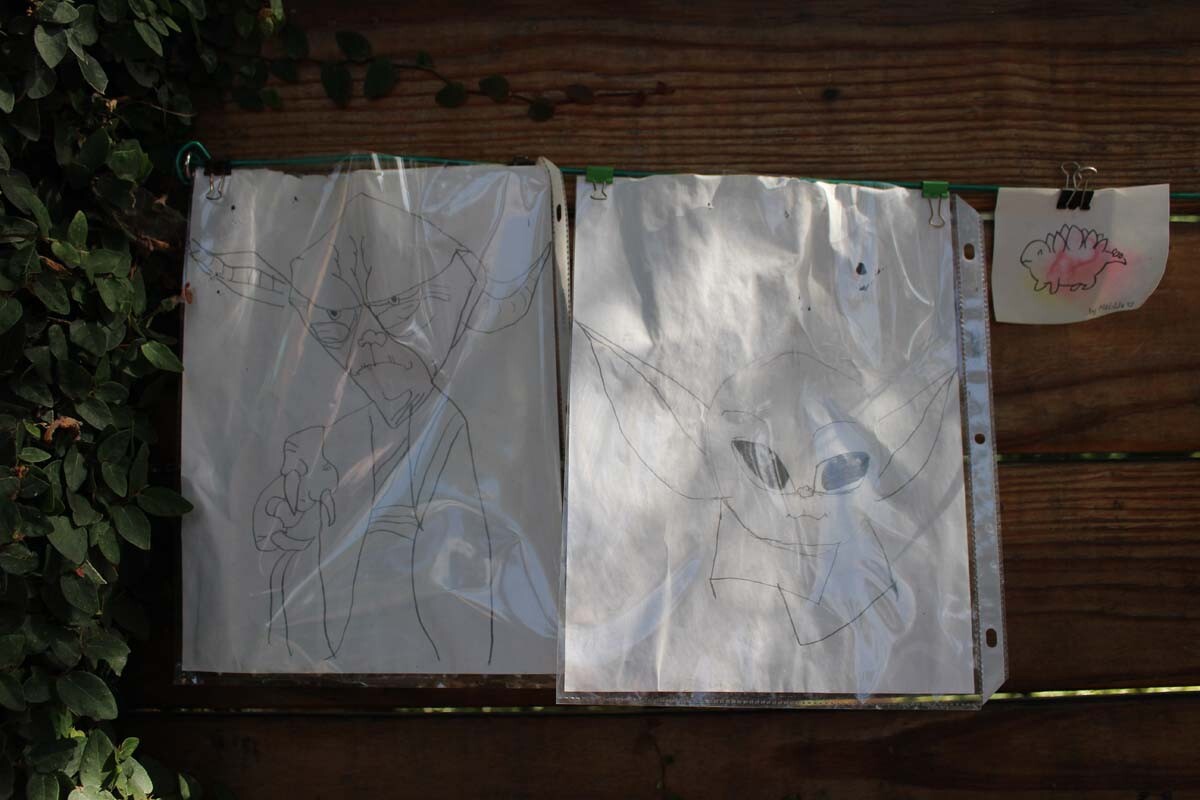 A pair of drawings of Yoda and Baby Yoda hang next to each other on Dan Fields’ Los Feliz fence gallery.