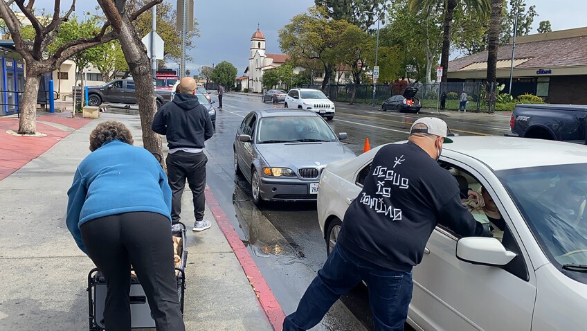 East Side Riders Bike Club members pass food to those waiting in cars