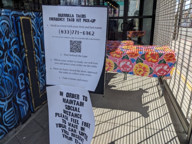 Signs posted in front of Guerrilla Tacos in downtown Los Angeles explaining its new system for picking up orders during the coronavirus pandemic and resulting quarantine. | Leo Duran/LAist