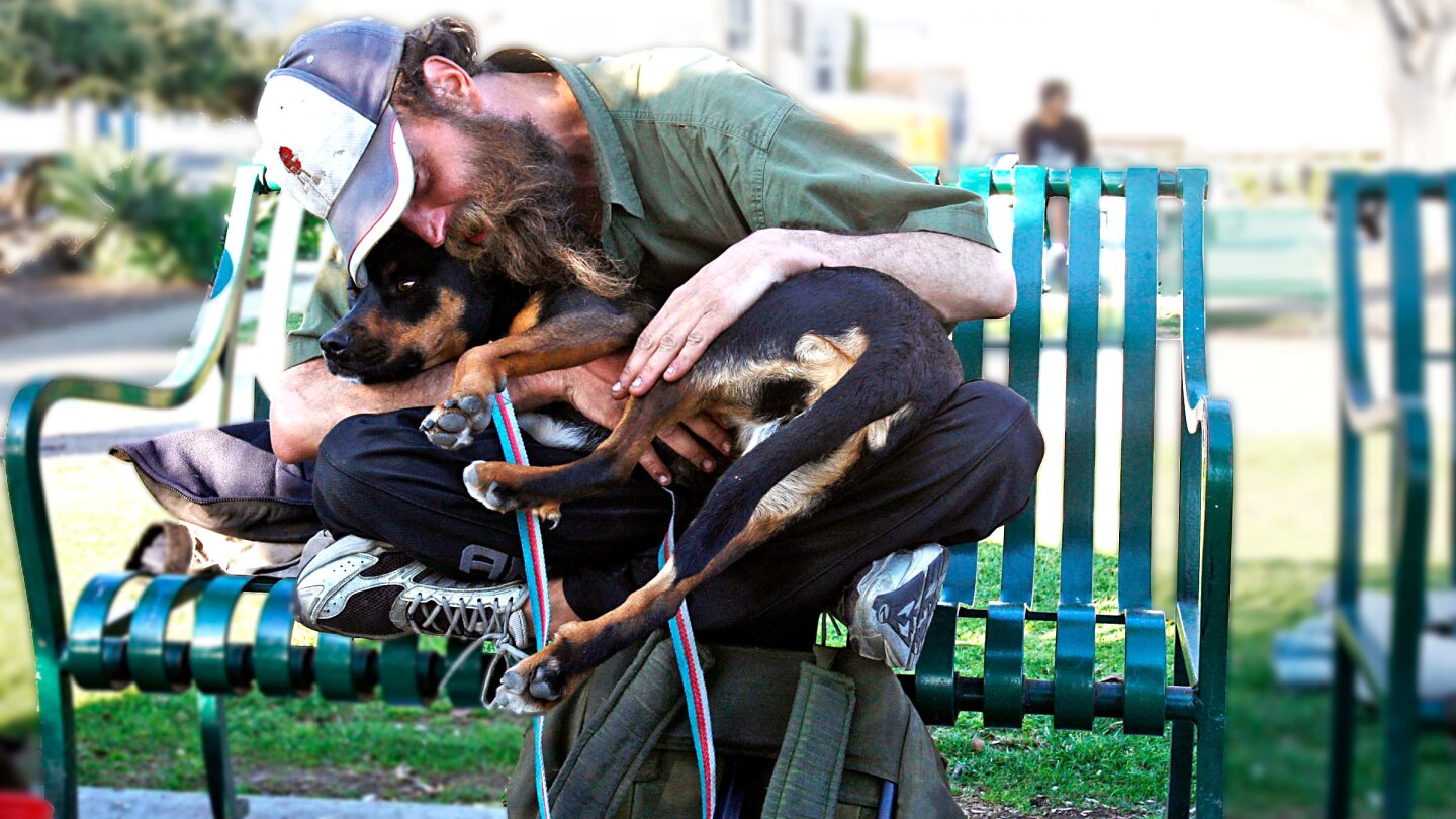 A homeless man named Shaggy cozies up with his dog, 2Toes, on a park bench in Santa Monica. | photo Luis Sinco/Los Angeles Times via Getty Images
