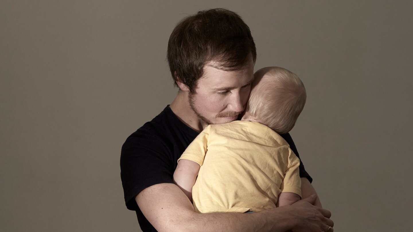 A man holds his infant child in his arms.