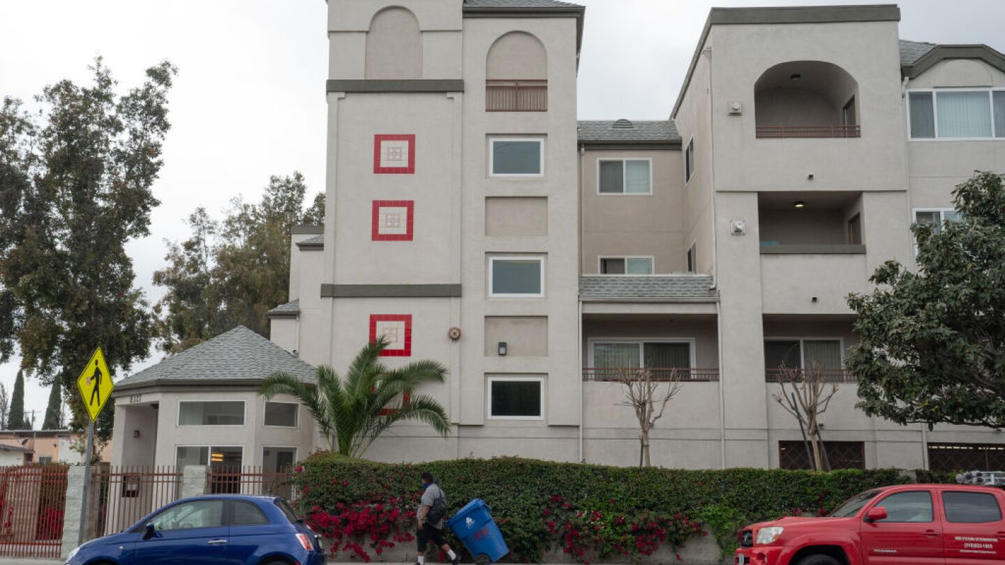 A person pulls a trash container past an apartment building in South Los Angeles, California, U.S. on Tuesday, April 13, 2021.