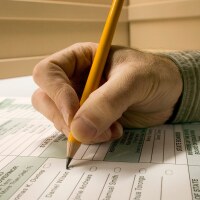 Man marking election ballot with pencil, close-up of hands | Andy Sacks/Getty Images