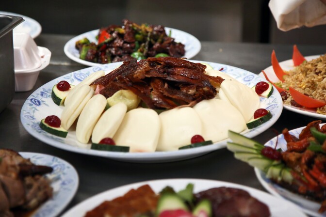 An image of a spread of Chinese dishes, with peking duck centered as the focus.