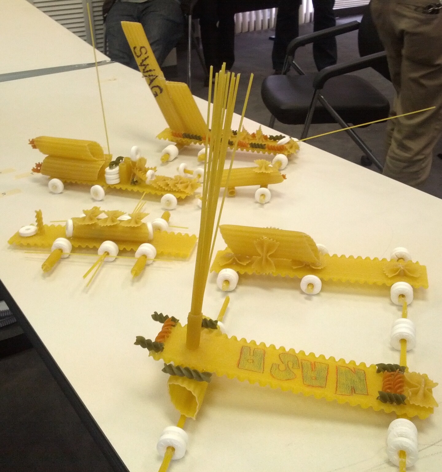 Several rovers made out of dried pasta are laid out on a table.