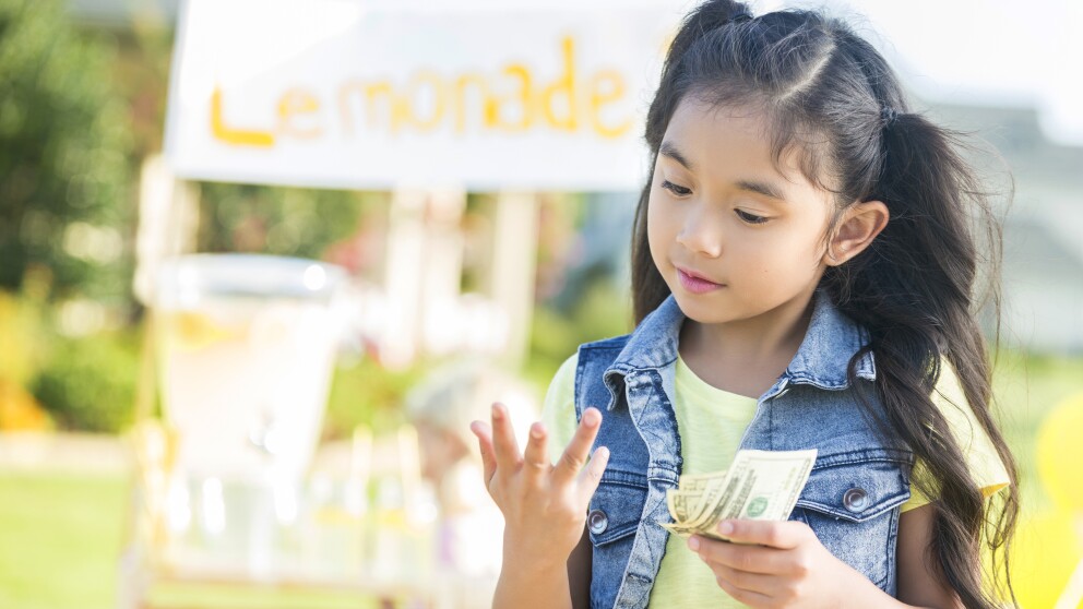 Young girl counts money made from lemonade stand