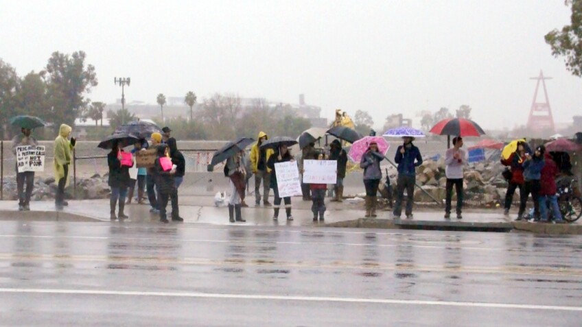 Demonstrators hold signs along Chapman Ave. next to the Santa Ana River | photo by Nick Gerda/Voice of OC