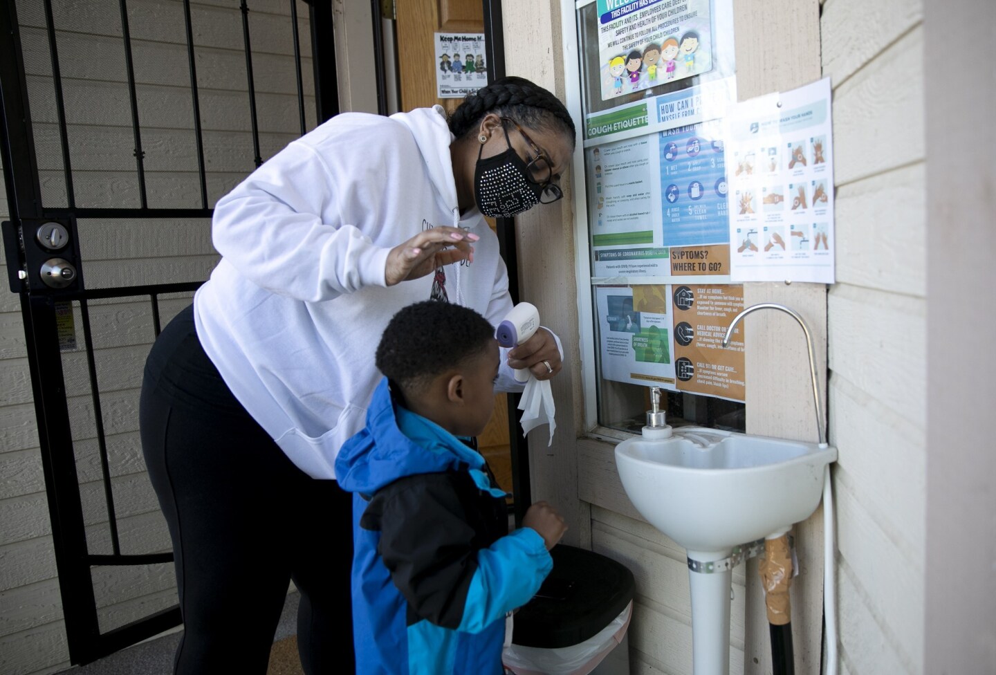 Family daycare provider Lucre-ce Lester takes a student’s temperature as he arrives for the day at her home-based daycare in Antioch on February. 17, 2021.