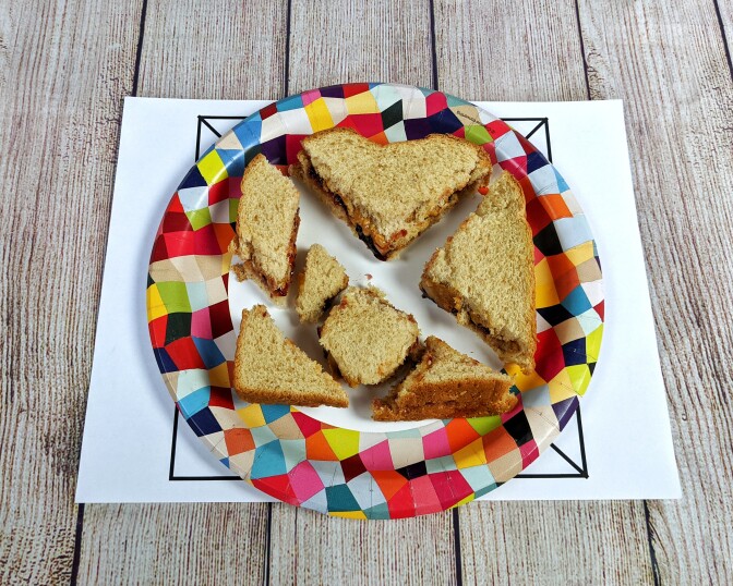 A tangram made out of a cut up peanut butter and jelly sandwich.