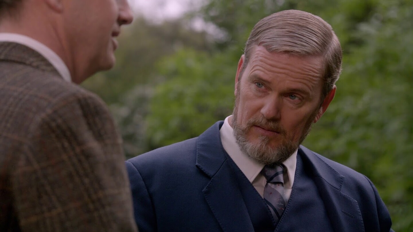 The Doctor Blake Mysteries Craig McLachlan in a blue suit talking to a man in brown suit