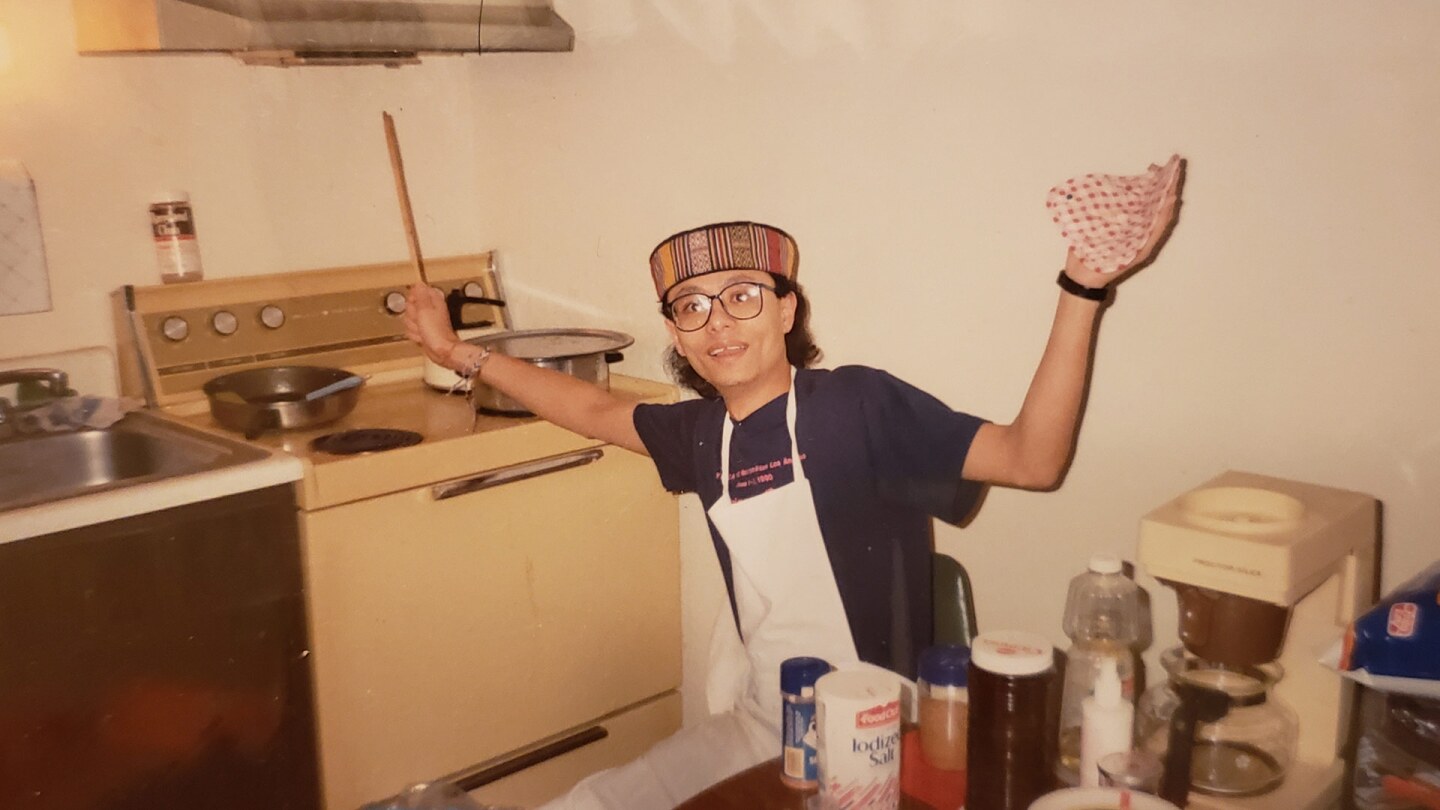 A man reaches for something on a stove next to him.