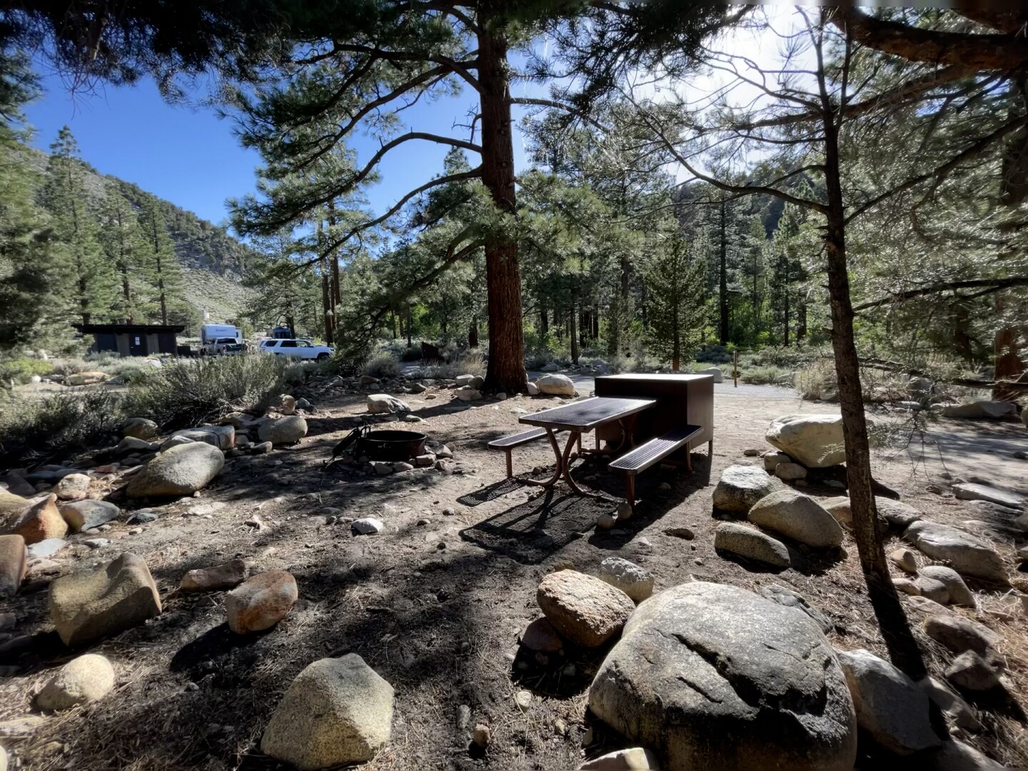 A campsite full of rocks, a small seating area surrounded by trees.