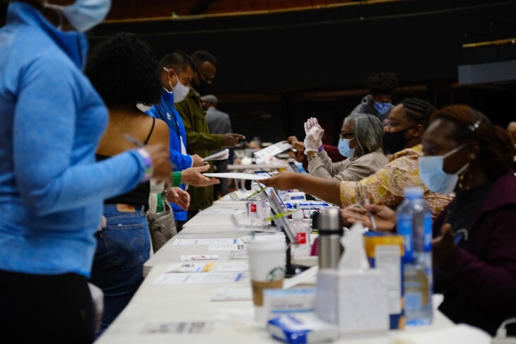Busy poll workers move voters through the vote center at the Forum in Inglewood. | Al Kamalizad for LAist