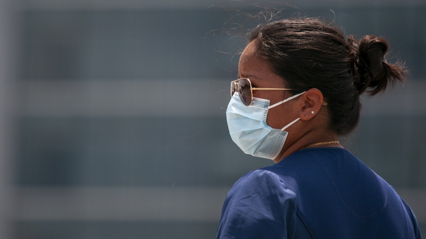 A medical technician wears a face mask at a drive-thru testing site for COVID-19.