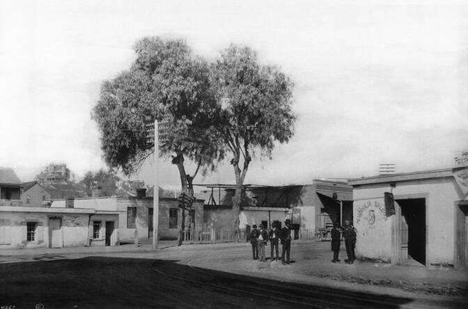 Six men stand ouside of the Magnolia Saloon at New High Street and Marchessault Street, Sonora Town, 1885-1887