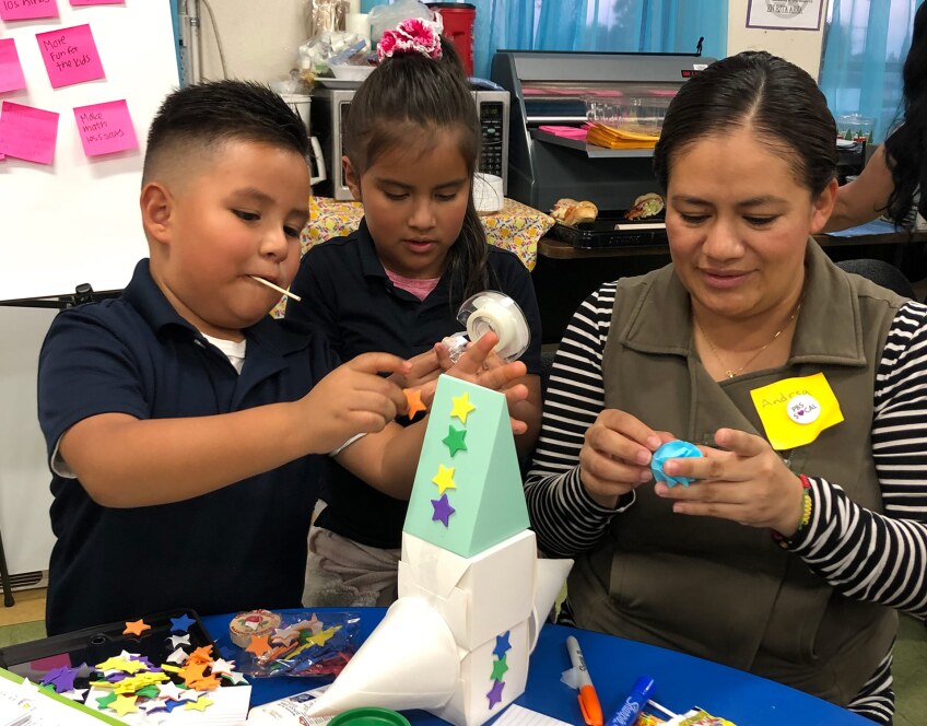 a mom works on a craft with two kids