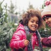 Two smiling children in puffy, colorful coats stand near snowy pine trees. istock