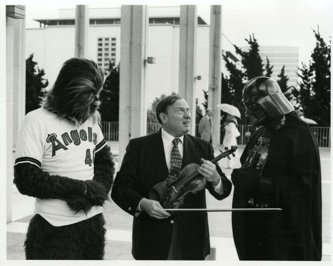 Concertmaster Sidney Harth, Chewbacca in an Angels jersey and a costumed Darth Vader promote the Music from Outer Space concert at Anaheim Stadium after "Star Wars" was released | Los Angeles Philharmonic Archives