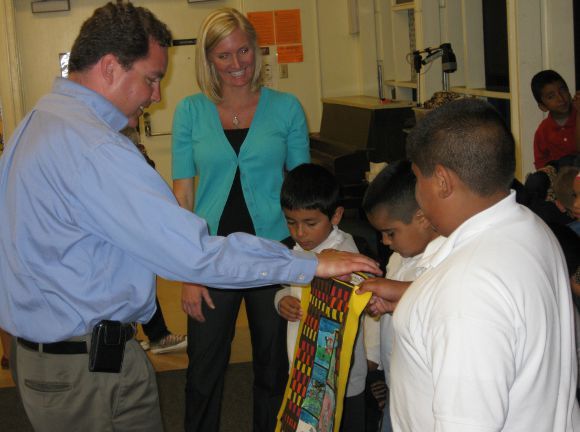 Children are presenting a story quilt they created to San Diego School Board Member Richard Barrera.