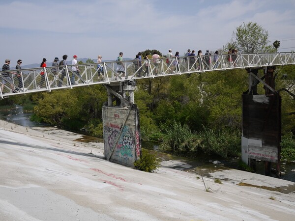 Walkers cross the pedestrian bridge over the river | Photo by George Villanueva