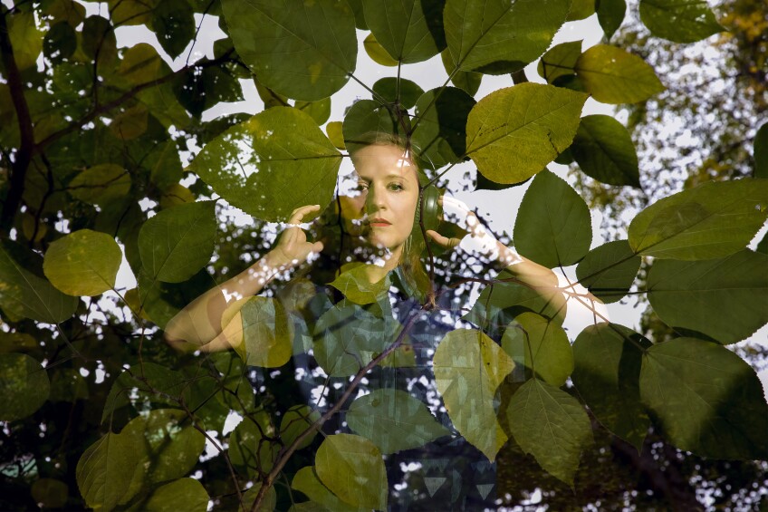 A woman wearing headphones overlaid with leaves