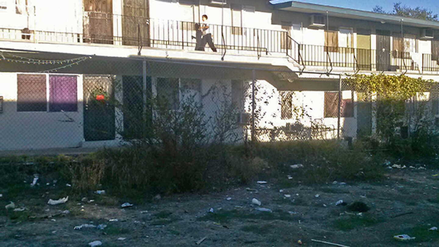 The vacant lot sits in between two apartment buildings with only a chain link fence as a barrier.