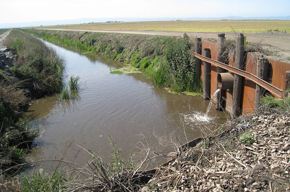 Drainage Canal with Water Pouring from Metal Pipe