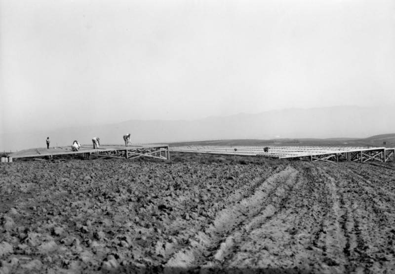 Men are shown in an open lot starting construction on what will soon become the Olympic Village in Baldwin Hills.