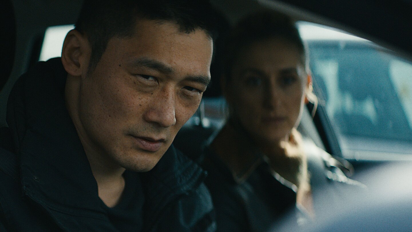 Alf and colleauge look out a car window. | Still from "Follow the Money" Season 3
