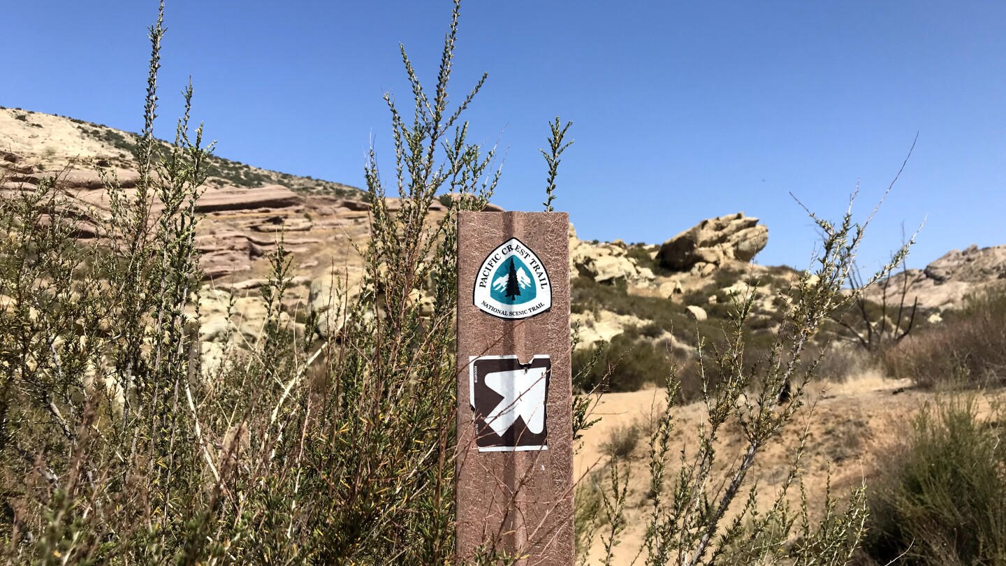 Pacific Crest Trail signpost against the sandstone rock landscape of Vasquez Rocks Natural Area Park.