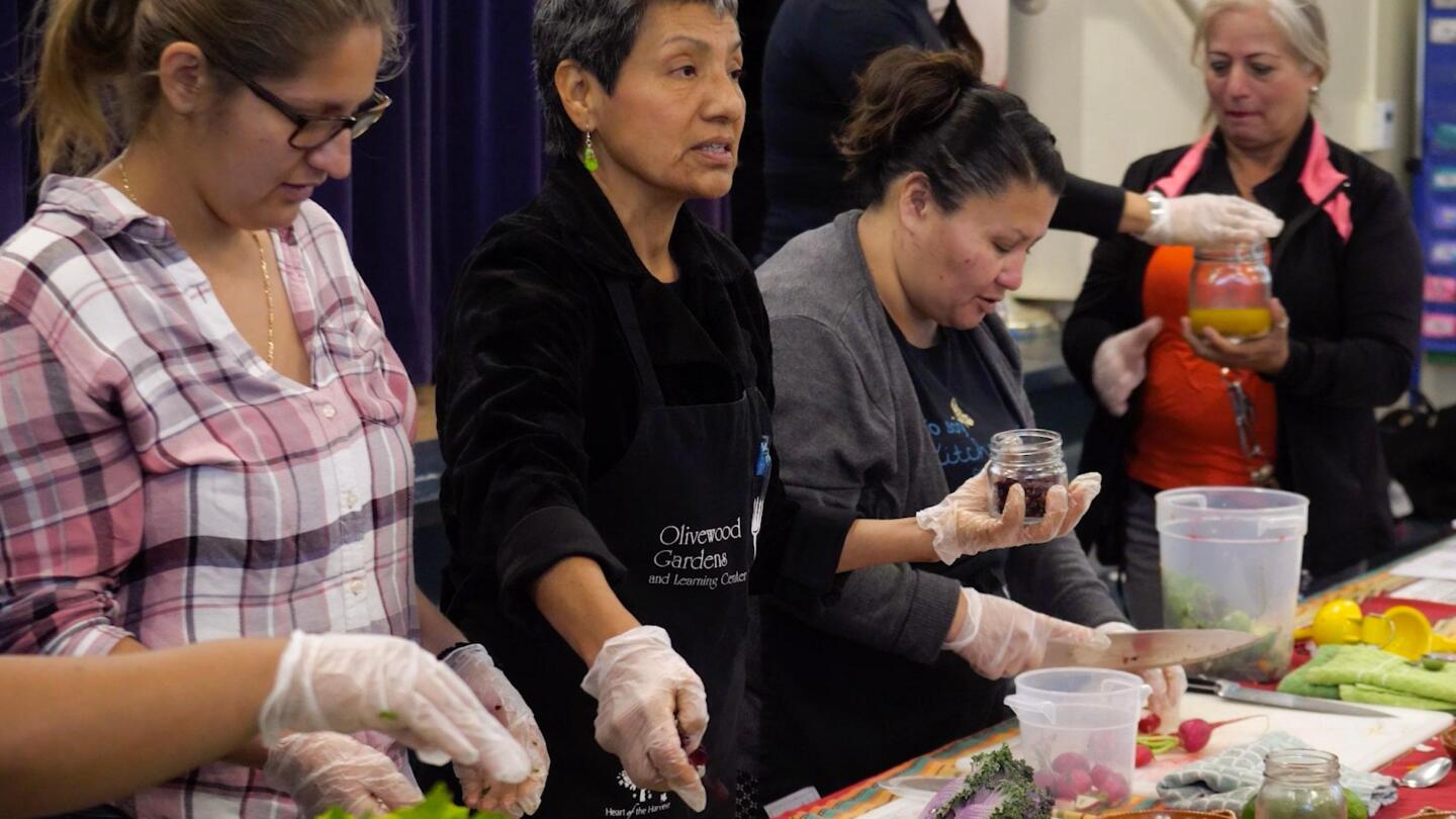 Women stand beside each other as they prepare food to serve.