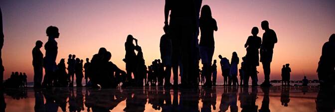 Silhouettes of people standing on a mirrored surface during golden hour | Mario Purisic / Unsplash
