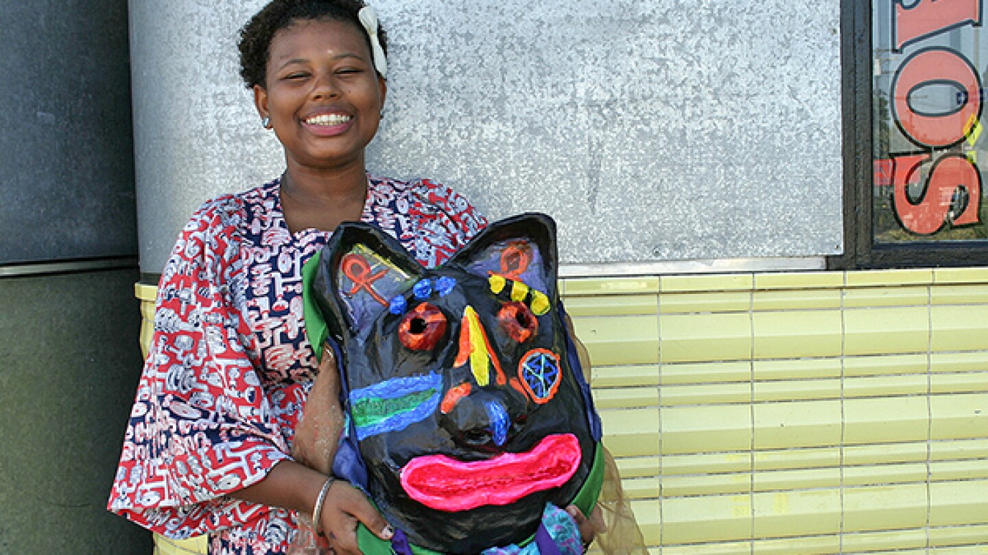 Lewa holds the object that connects her to her community-a mask made for the Day of the Ancestors