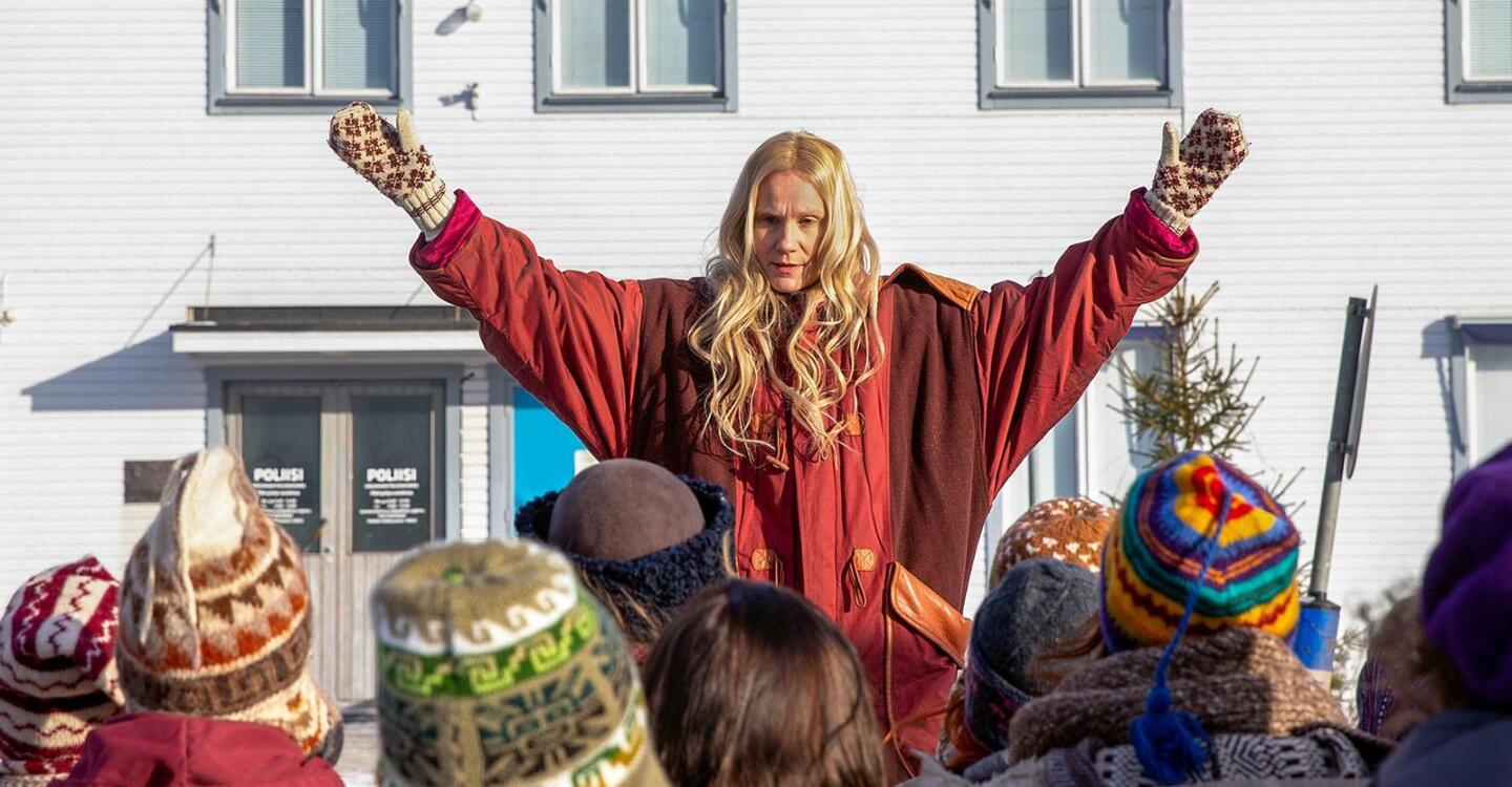 A person raises their arms in front of a crowd of people.
