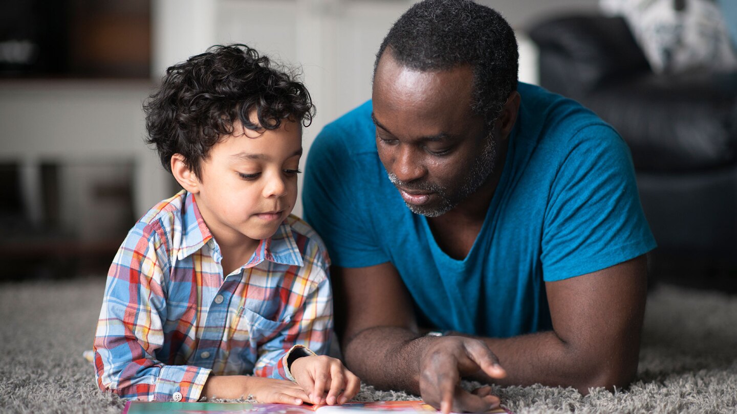 A man and a little boy read together.