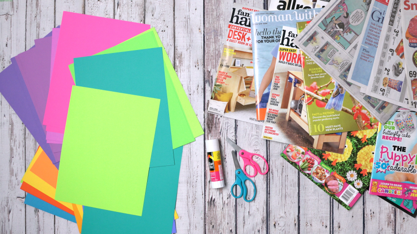 Magazines, paper, glue and scissors are laid out on a table.