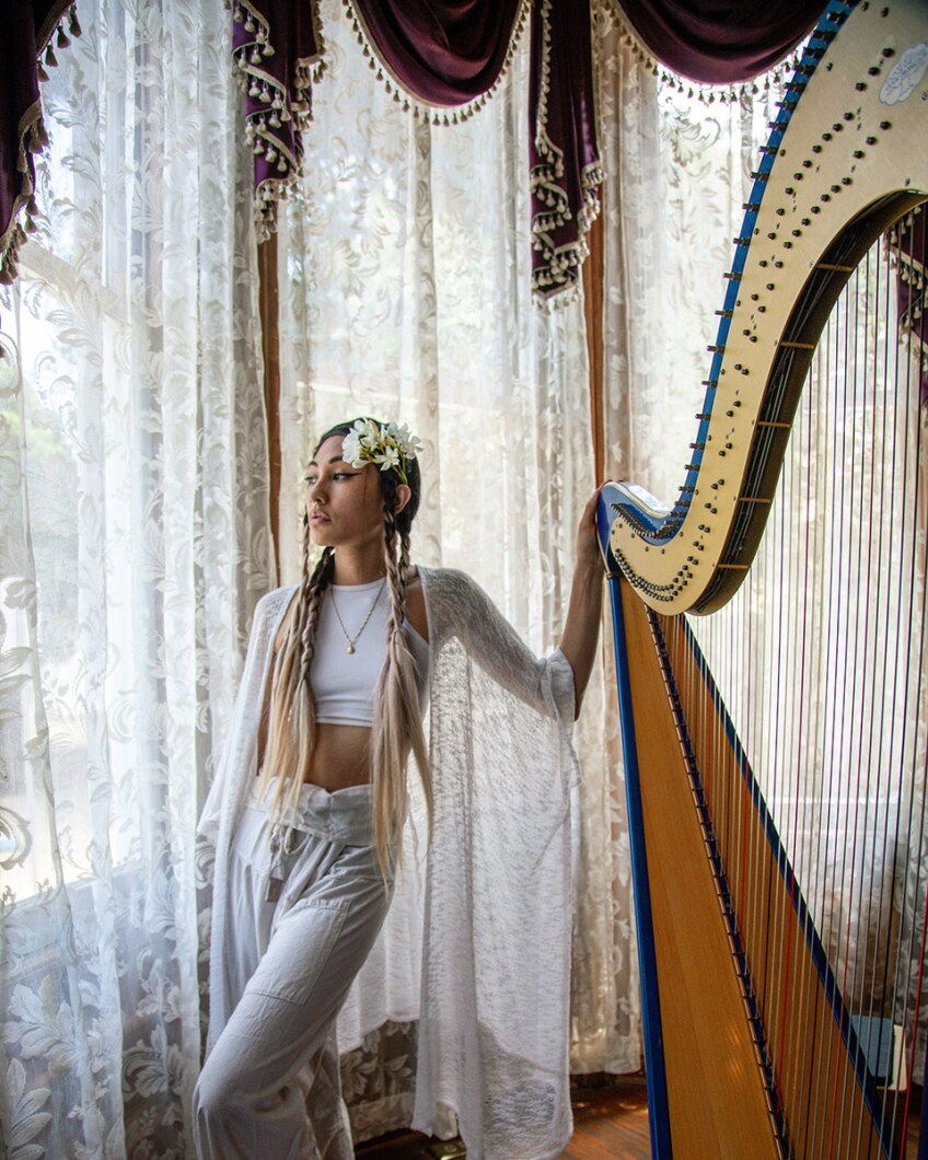 Low Leaf poses next to her harp inside the Perry House at Heritage Square Museum. | Azul Amaral
