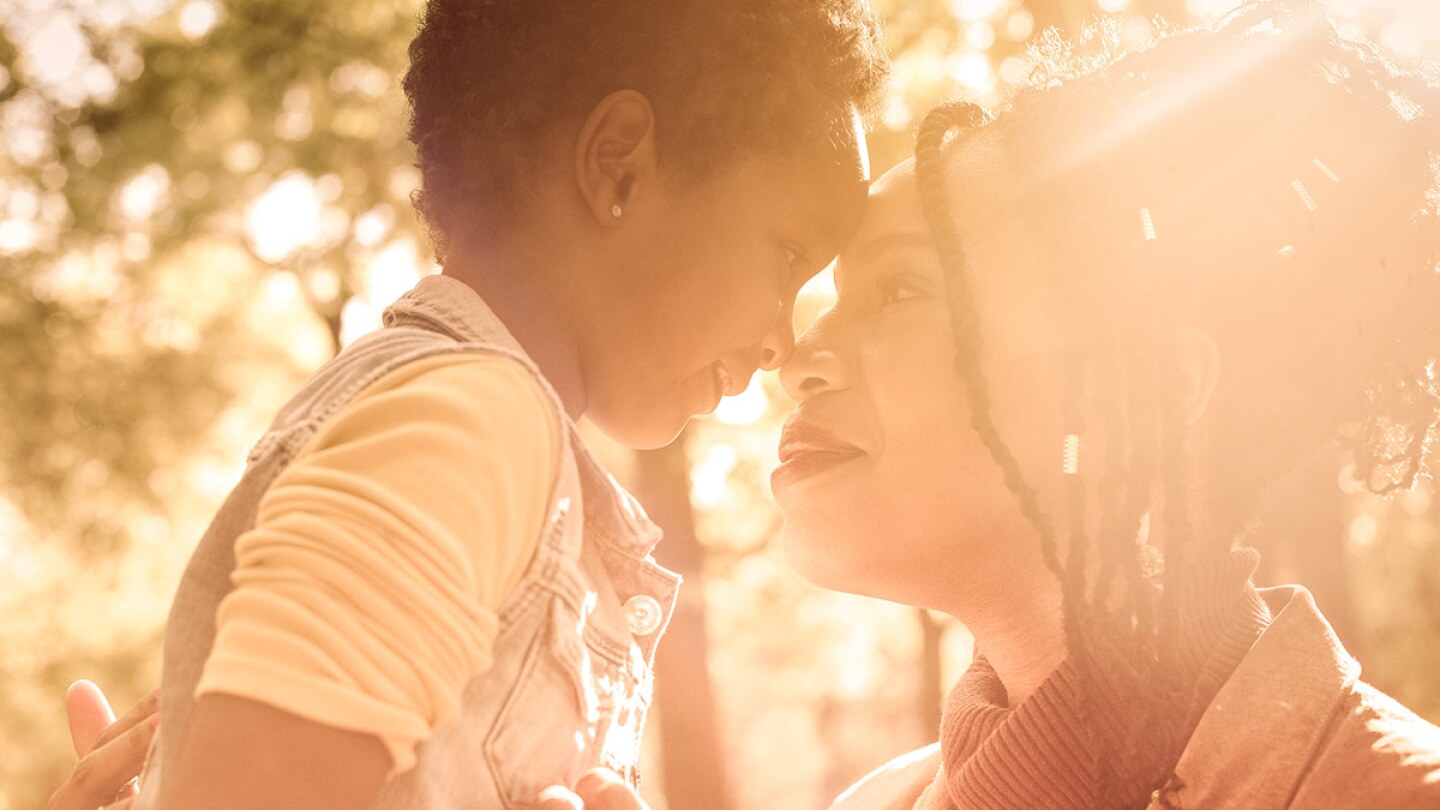 A mom looks into a small child's eyes as they are both enveloped in warm light