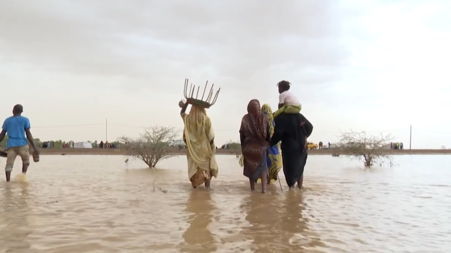 A group of people wade through flood water.