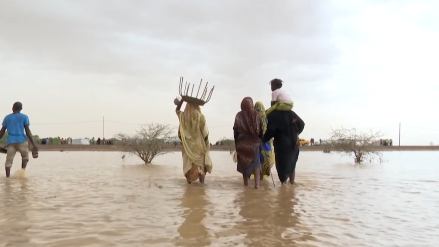 A group of people wade through flood waters.