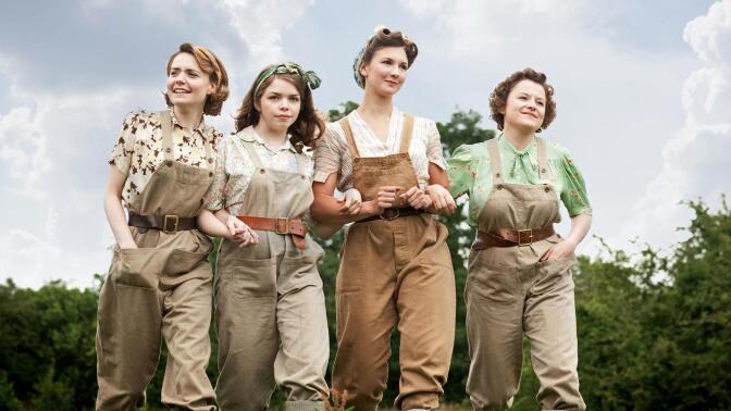 Four women arm in arm.