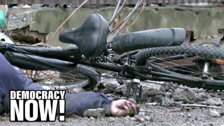 The hand of a corpse on the ground next to a toppled bicycle.